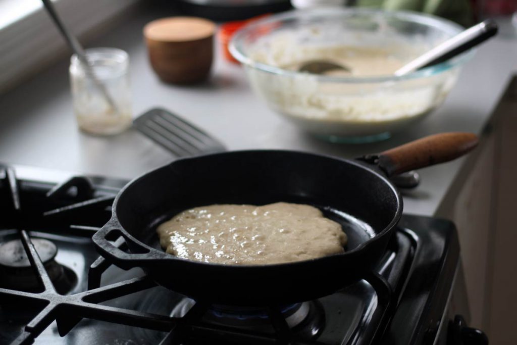 Delicious and nourishing rustic sourdough pancake cooking in the cast iron pan.