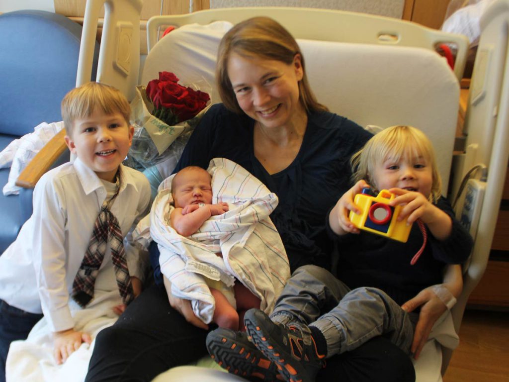 Mom with newborn baby and brothers.